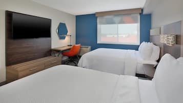 Une chambre d’hôtel équipée d’une télévision à écran plat, d’un bureau avec une chaise, de deux lits et d’une fenêtre donnant sur un paysage agréable.