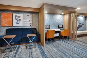 A hotel room with a blue sofa, two chairs, a desk with a computer, and a large window with a view. - Holiday Inn Express & Suites Fredericton by IHG (Fredericton)