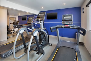 A gym with treadmills, stationary bikes, and a mirrored wall.