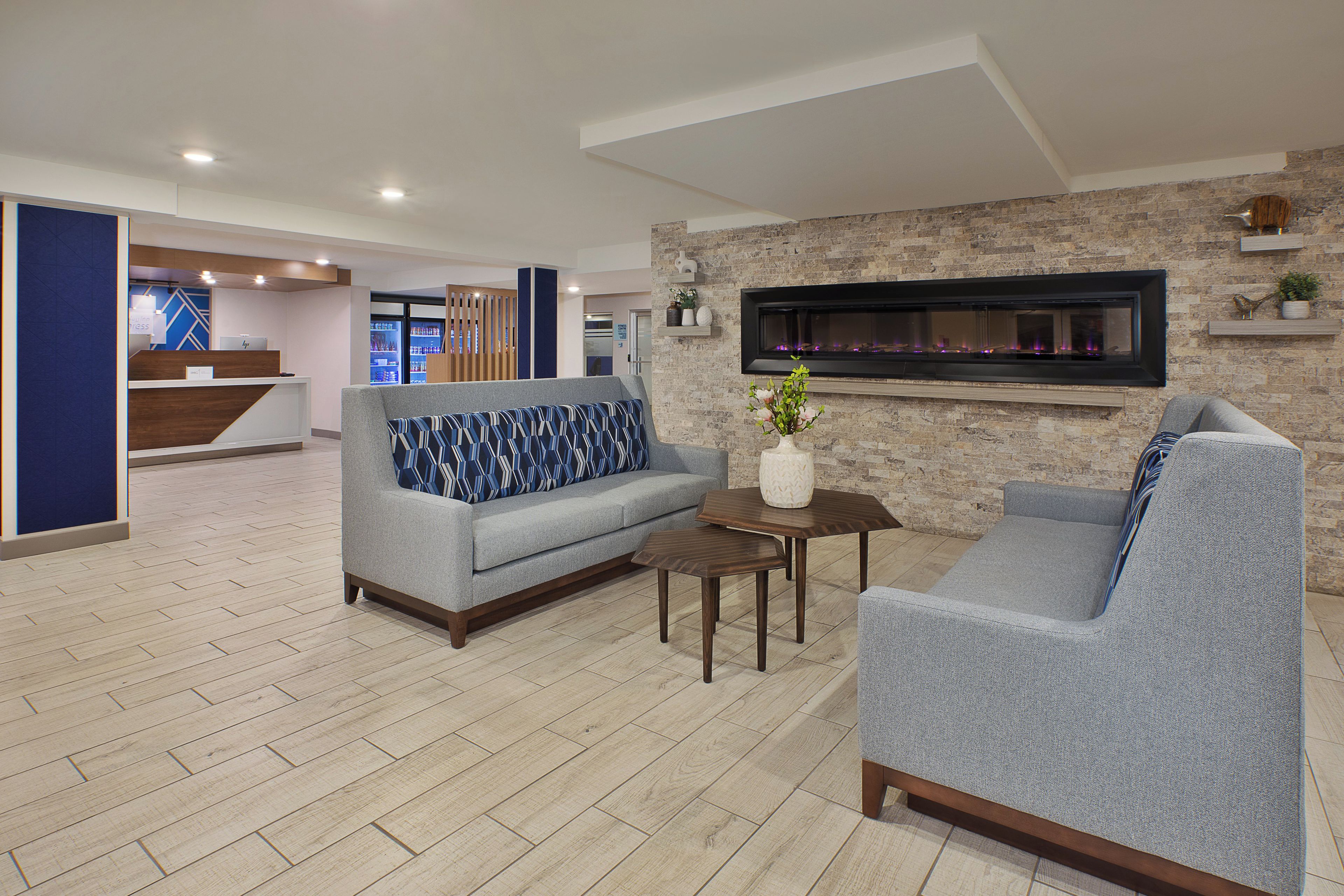 A modern lobby with a sofa, armchair, and a small table with a vase.