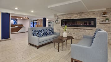 A modern lobby with a sofa, armchair, and a small table with a vase.