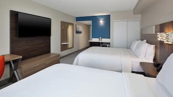 Une chambre d’hôtel avec deux lits, un bureau, une télévision, un miroir et une table de chevet.