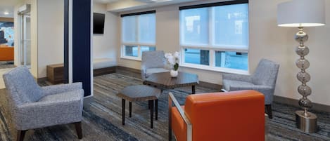 A hotel room with a seating area, a table, and a lamp.