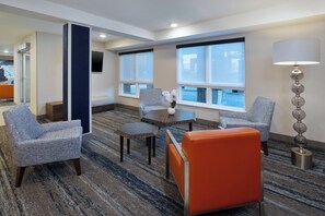 A hotel room with a seating area, a table, and a lamp. - Holiday Inn Express & Suites Fredericton by IHG (Fredericton)