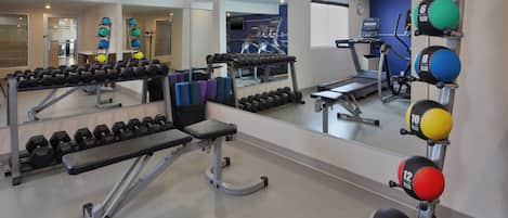 A gym with exercise equipment, mirrors, and a treadmill.