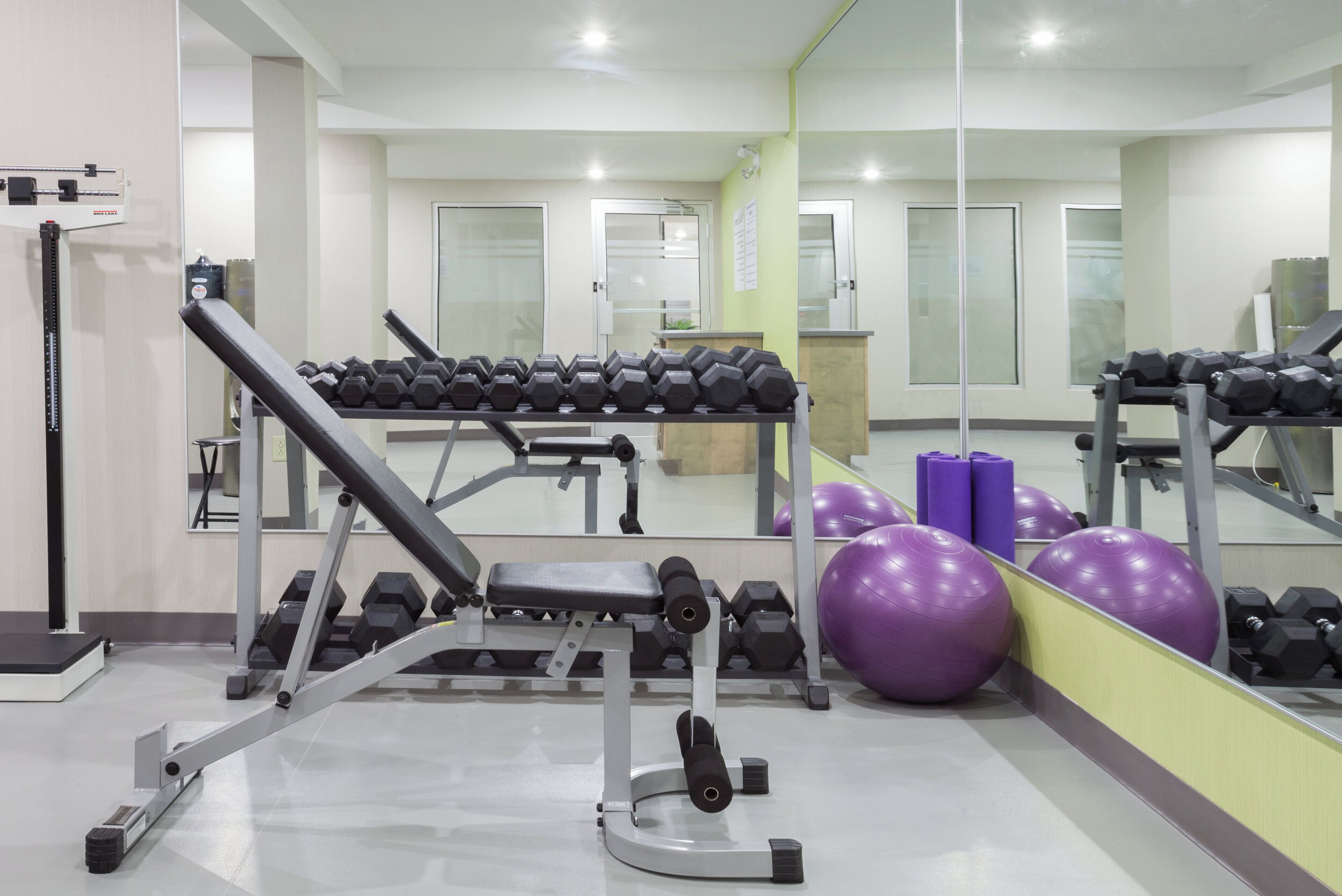 Un gimnasio con equipo de ejercicio, incluyendo mancuernas y una prensa de banca.