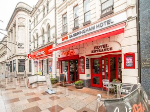 A hotel entrance with a red awning, a sign for Ladbrokes, and a sign for Cafe Jazz. - Cardiff Sandringham Hotel (Cardiff)