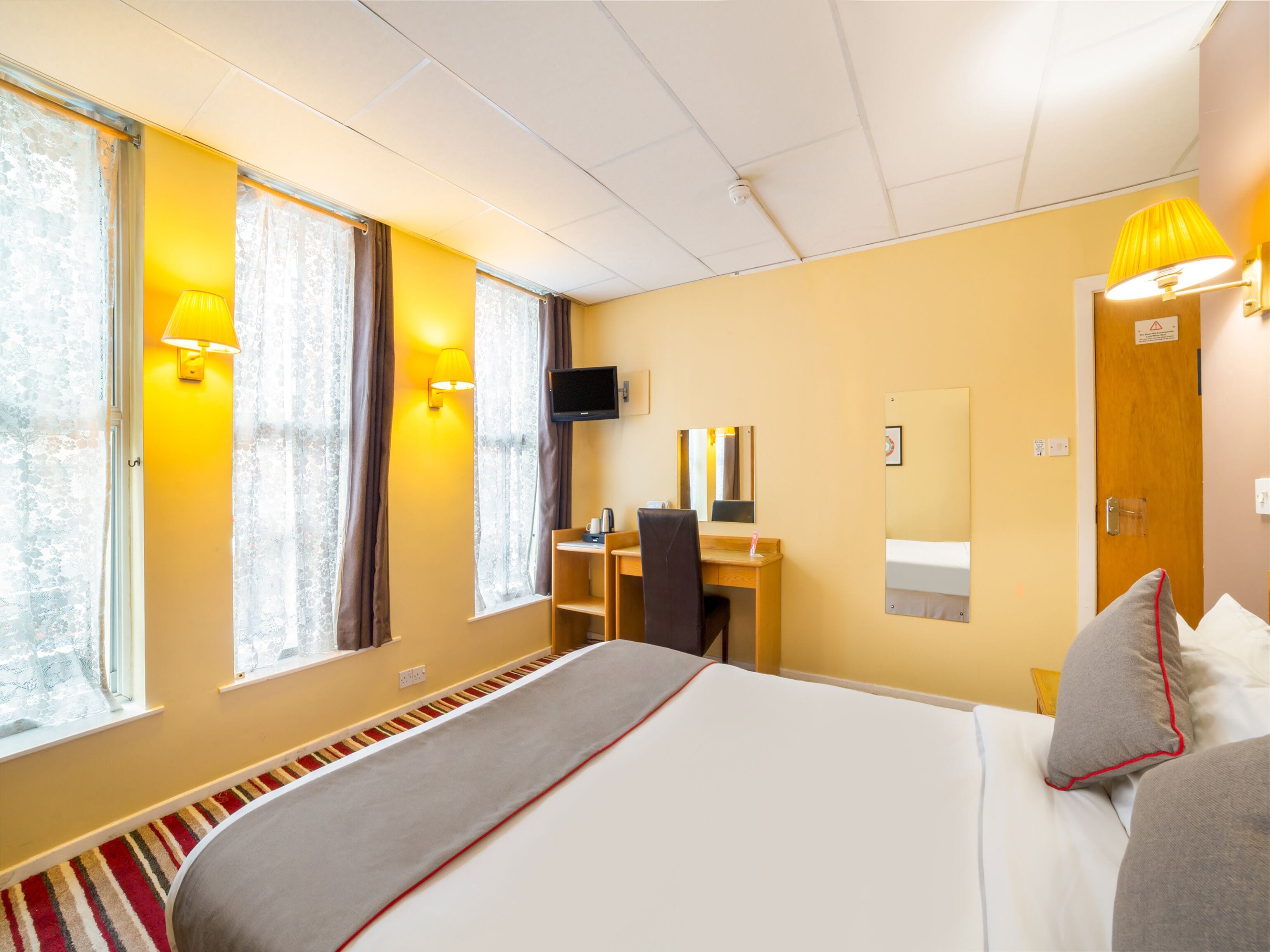 Une chambre d’hôtel équipée d’un lit, d’un bureau, d’une chaise et d’un téléviseur.