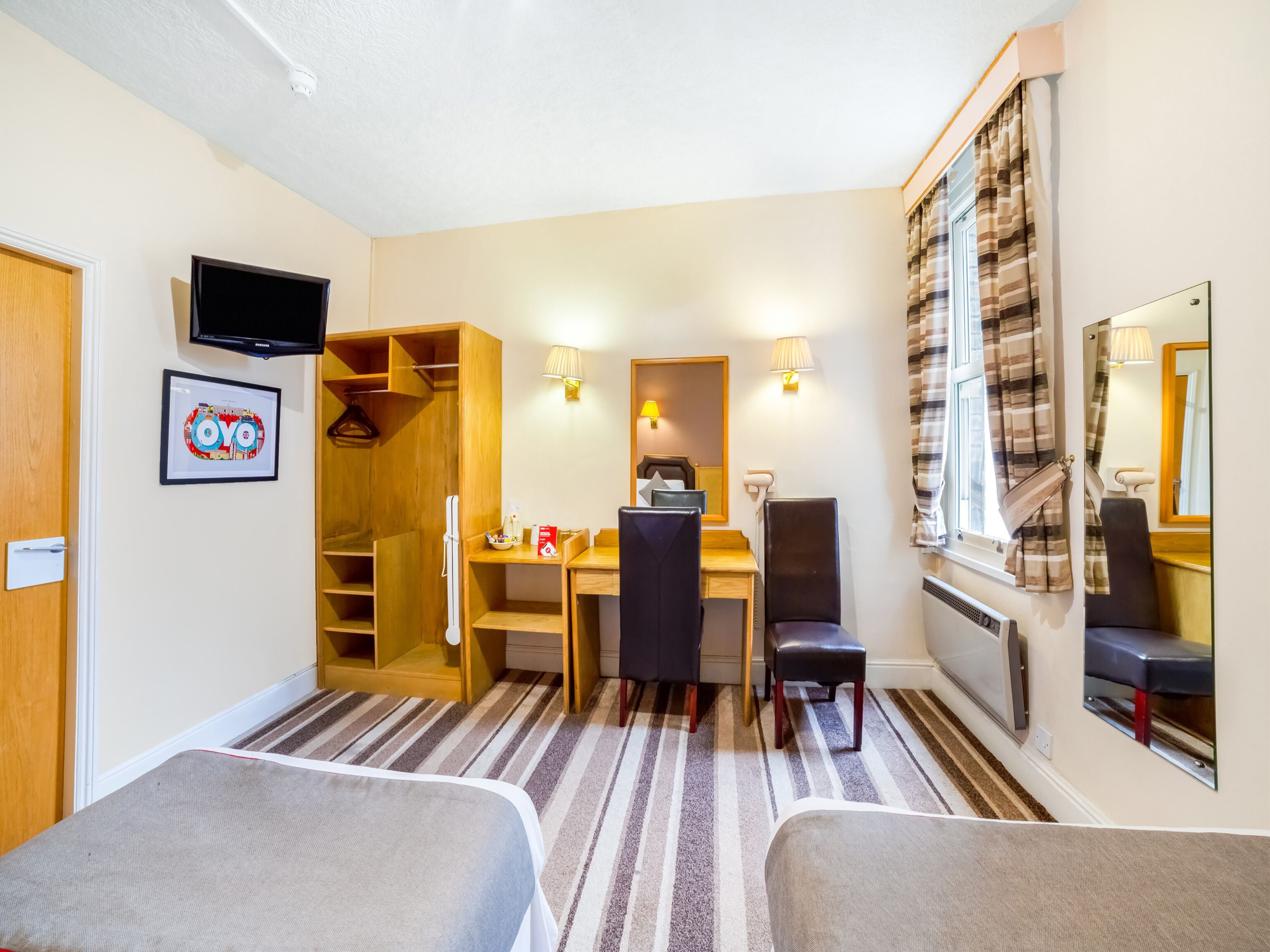 Una habitación pequeña con cama, escritorio, silla, televisor y armario.