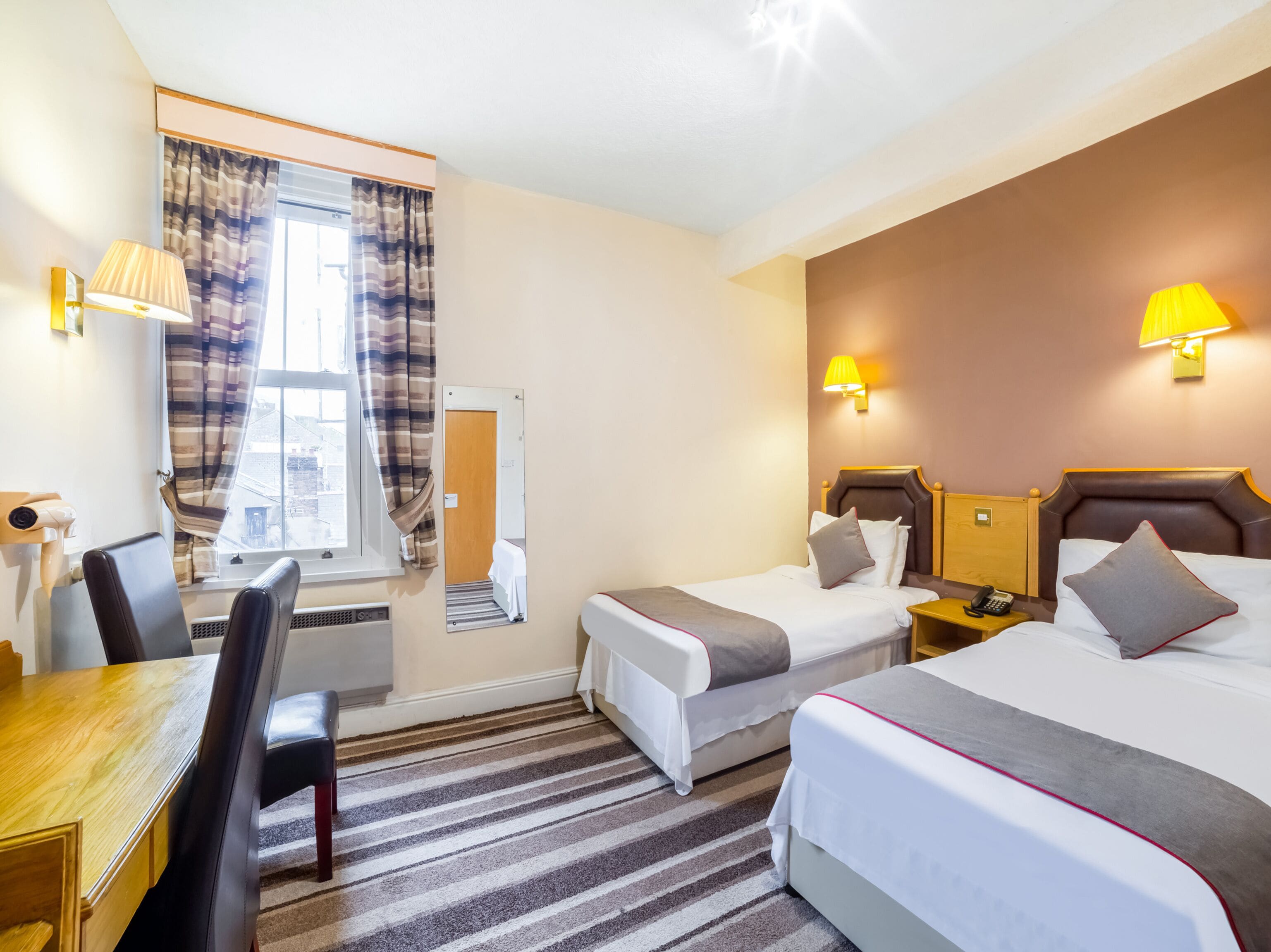 A hotel room with two beds, a desk, and a chair.