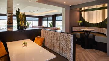 A modern restaurant interior with high-backed booths, a central dining table, and a curved seating area.