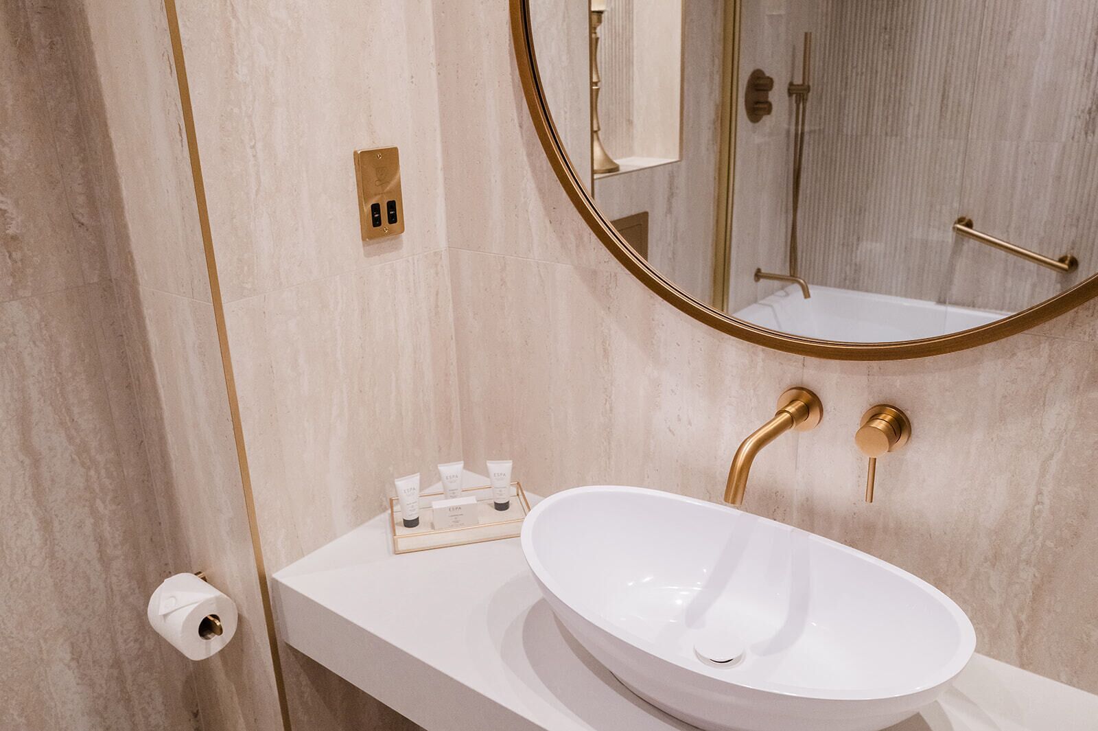 A bathroom with a white sink, gold fixtures, and a mirror.