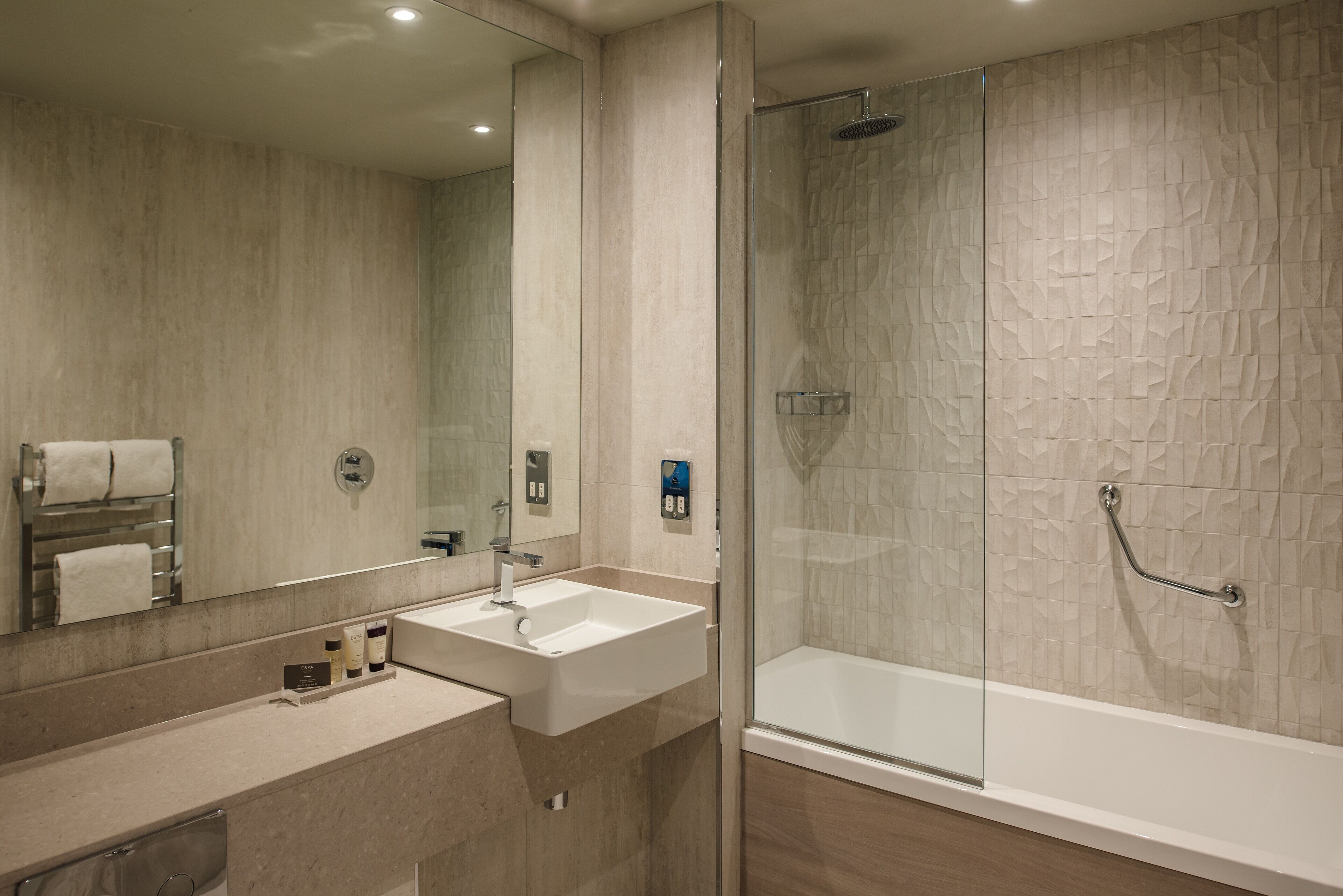 Un baño moderno con dos lavamanos, un espejo grande y una ducha con cerramiento de vidrio.