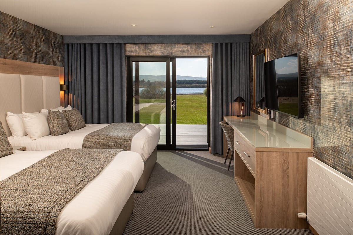 A modern hotel room with a large bed, a desk, and a TV.