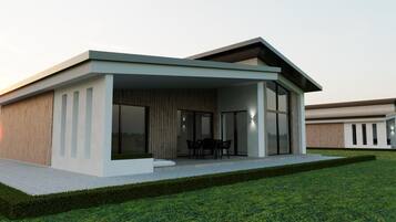 Una casa moderna con un porche cubierto, ventanas amplias y un césped cuidado.