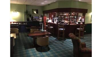 A bar area with a checkered floor, bar stools, and a counter with various bottles.