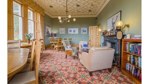 A cozy room with a patterned carpet, wooden furniture, a fireplace, and a bookshelf. - Mansfield House Hotel (Hawick)
