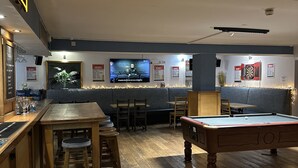 A bar area with a pool table, bar stools, and a television screen. - Harry's Hotel (Aberystwyth)