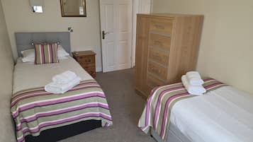 Une chambre avec deux lits, une armoire, une table de chevet, un miroir et une porte.