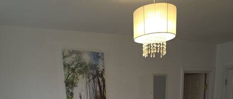 A hotel room with a bed, a nightstand, a lamp, a painting on the wall, and a door.