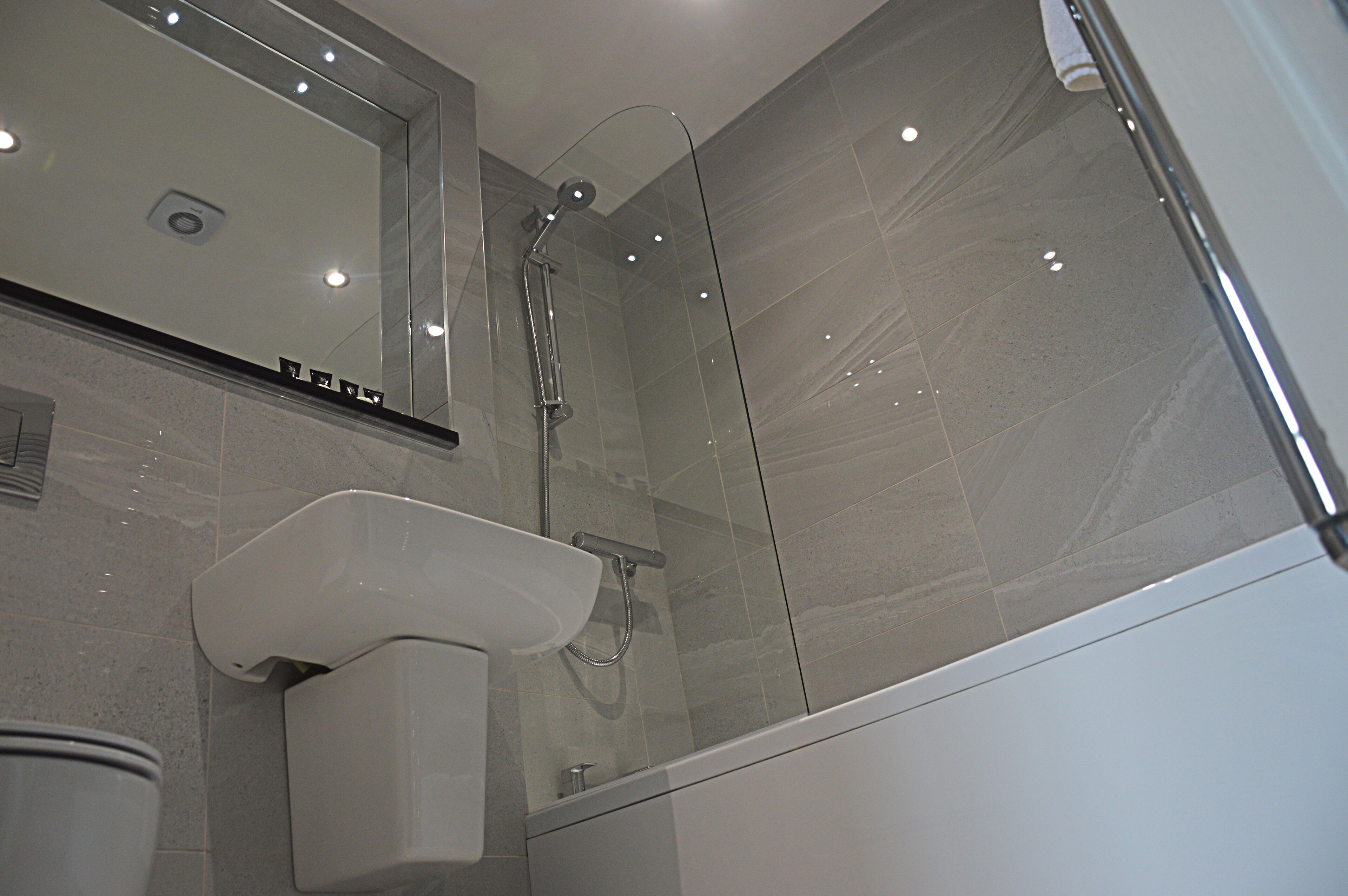 A modern bathroom with a glass shower enclosure, a white sink, and a mirror above the sink.