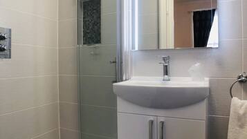 A modern bathroom with a glass-enclosed shower, a white sink, and a mirror above it.