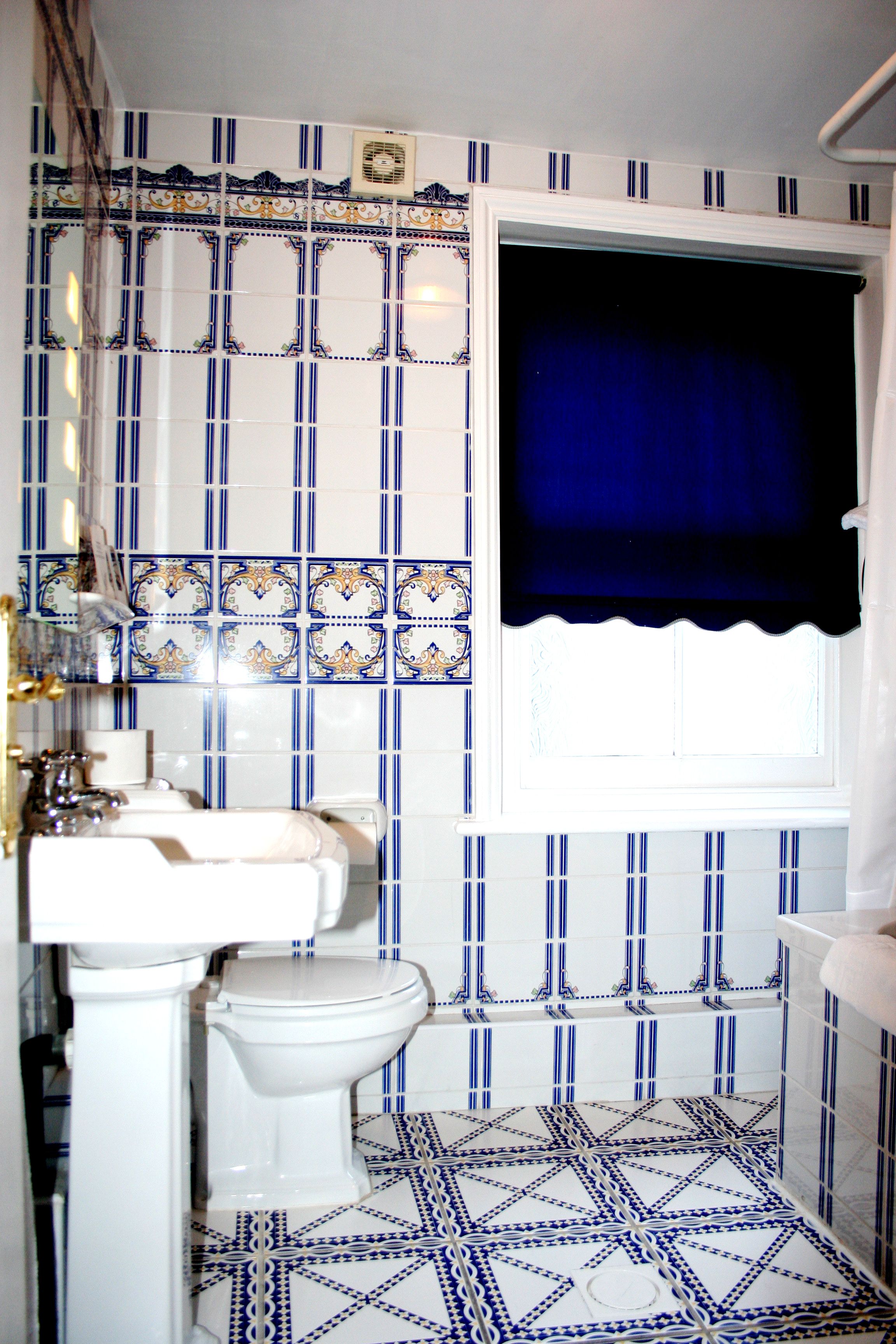 A bathroom with a toilet, sink, and window with a blue curtain.