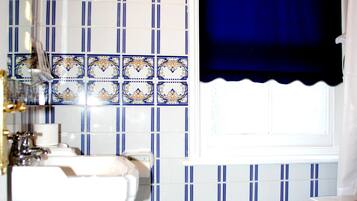 A bathroom with a toilet, sink, and window with a blue curtain.