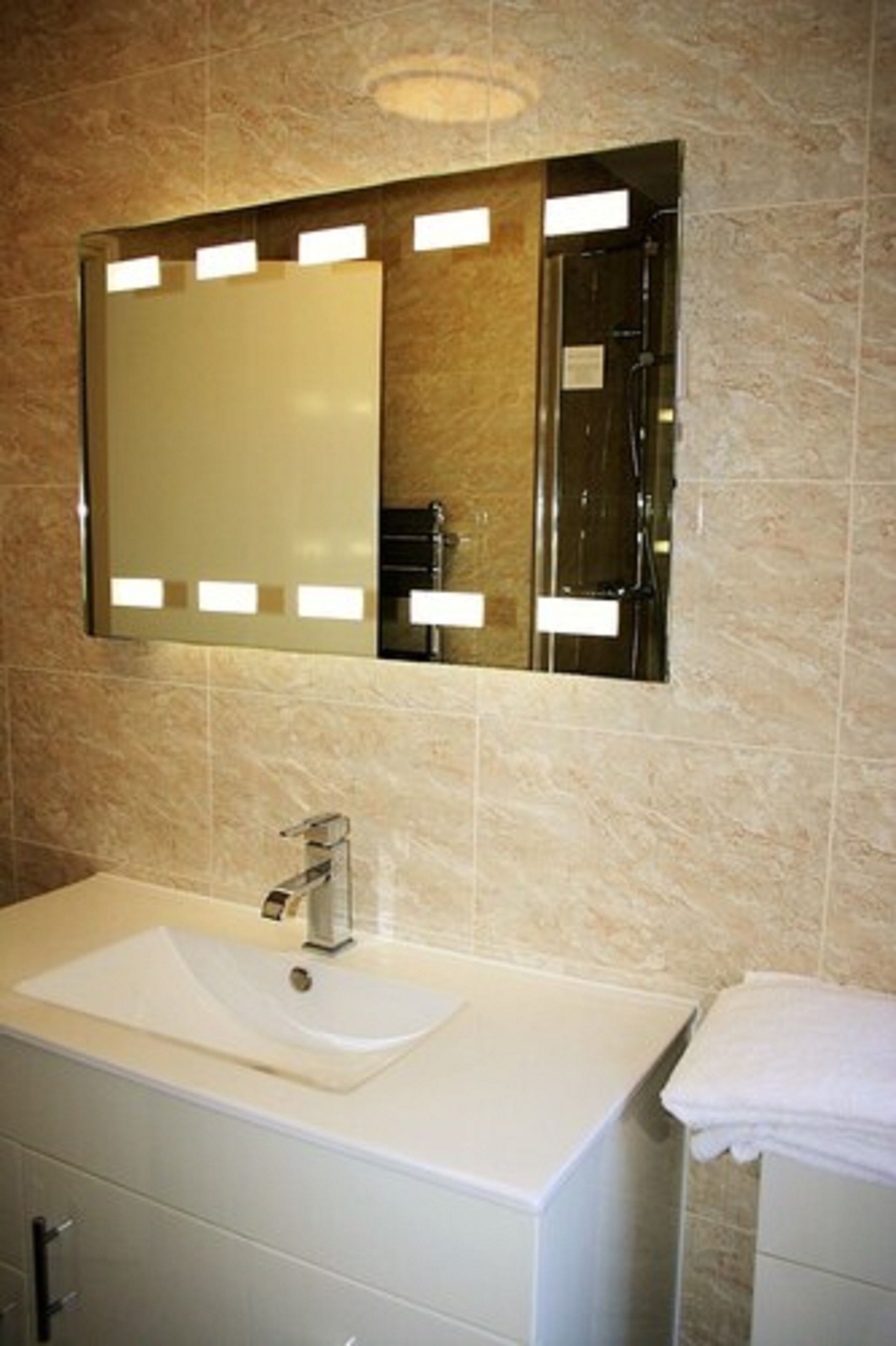 Une salle de bain avec un grand miroir, un meuble-lavabo et un porte-serviettes.