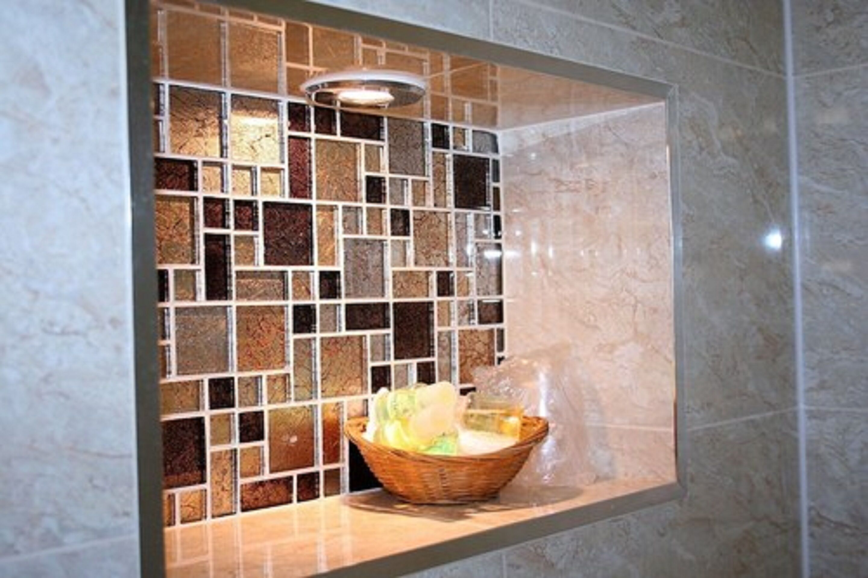 A bathroom with a tiled mosaic wall and a wicker basket on a countertop.