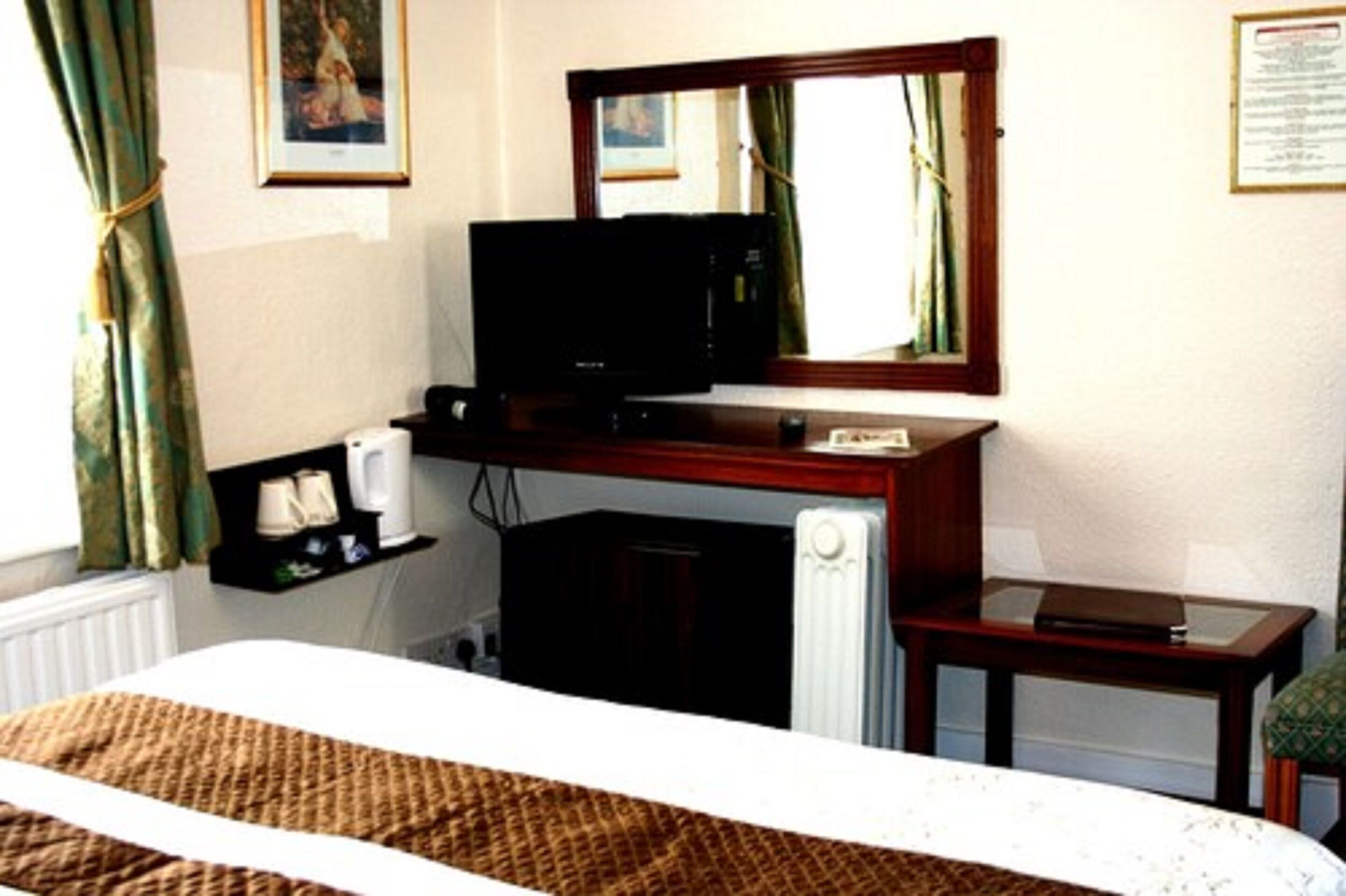 Ein Hotelzimmer mit einem Bett, einem Fernseher, einem kleinen Tisch und einer Heizung.