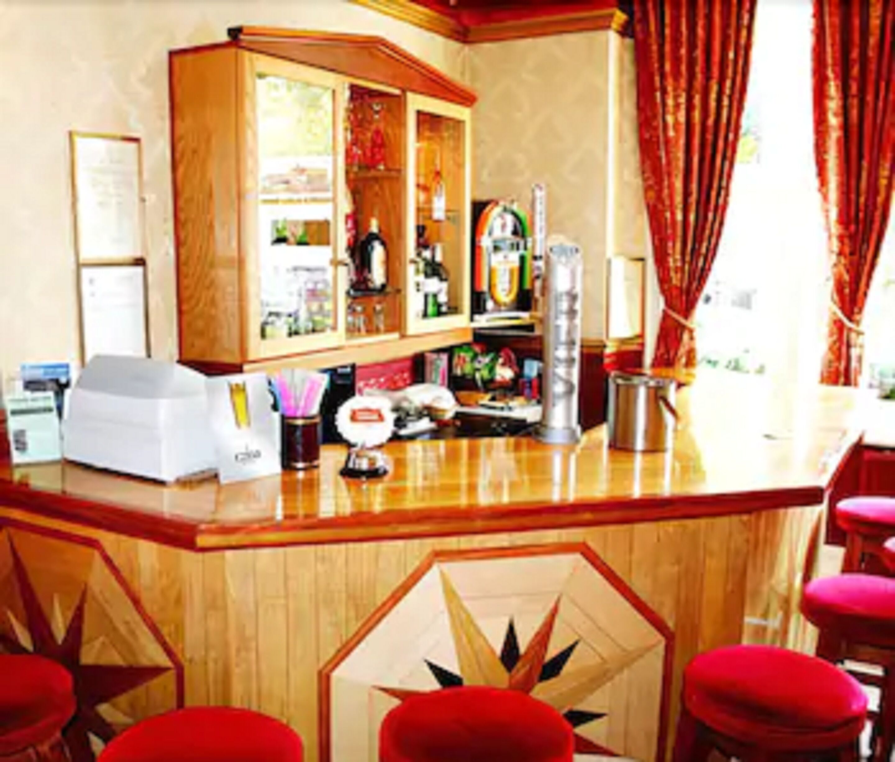 Angolo bar con un bancone in legno, sgabelli rossi e un motivo geometrico decorativo sulla parete.