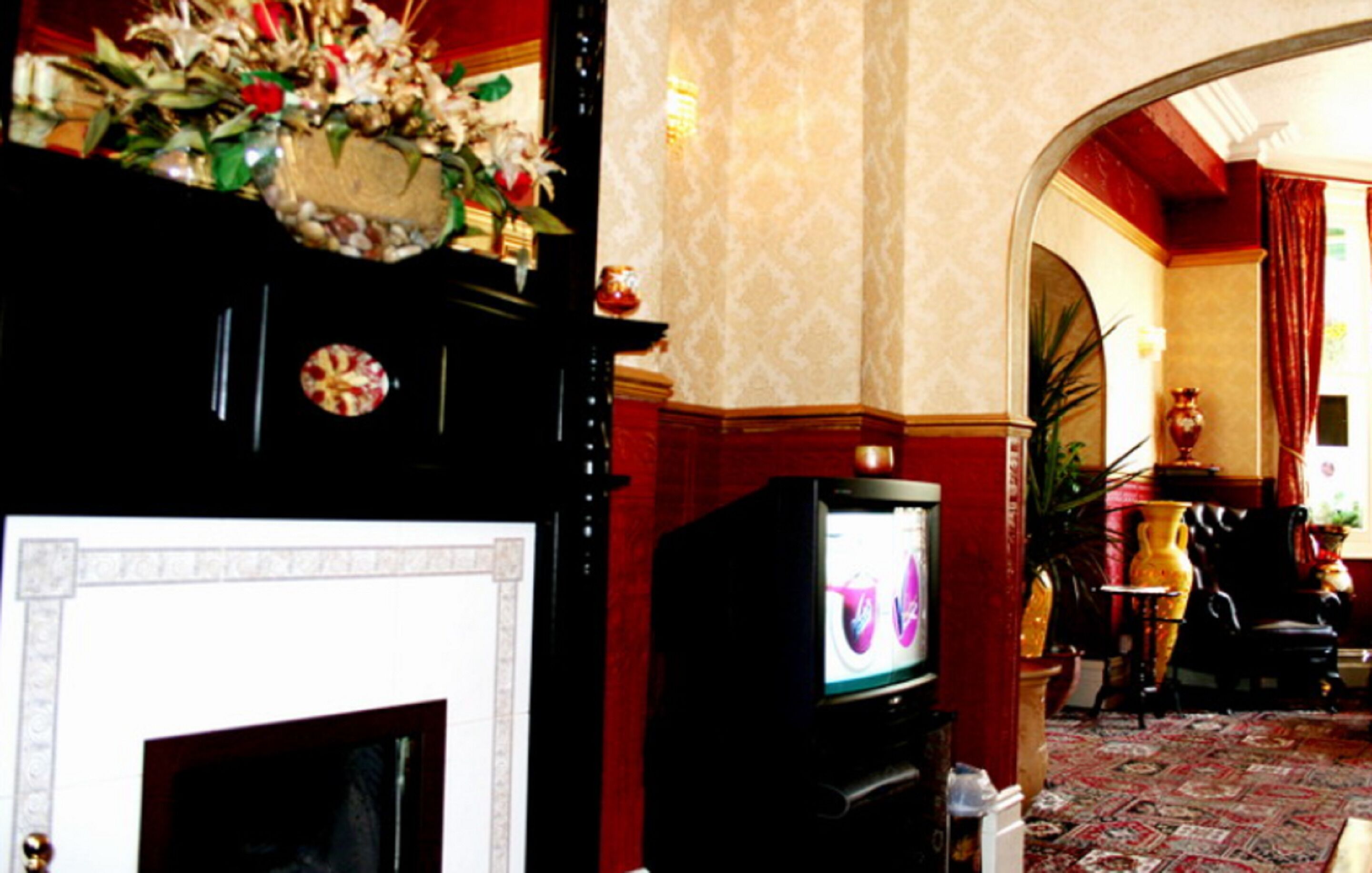 A room with a fireplace, a television, and a decorative mirror.