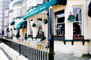 A row of terraced houses with outdoor seating and flower boxes.