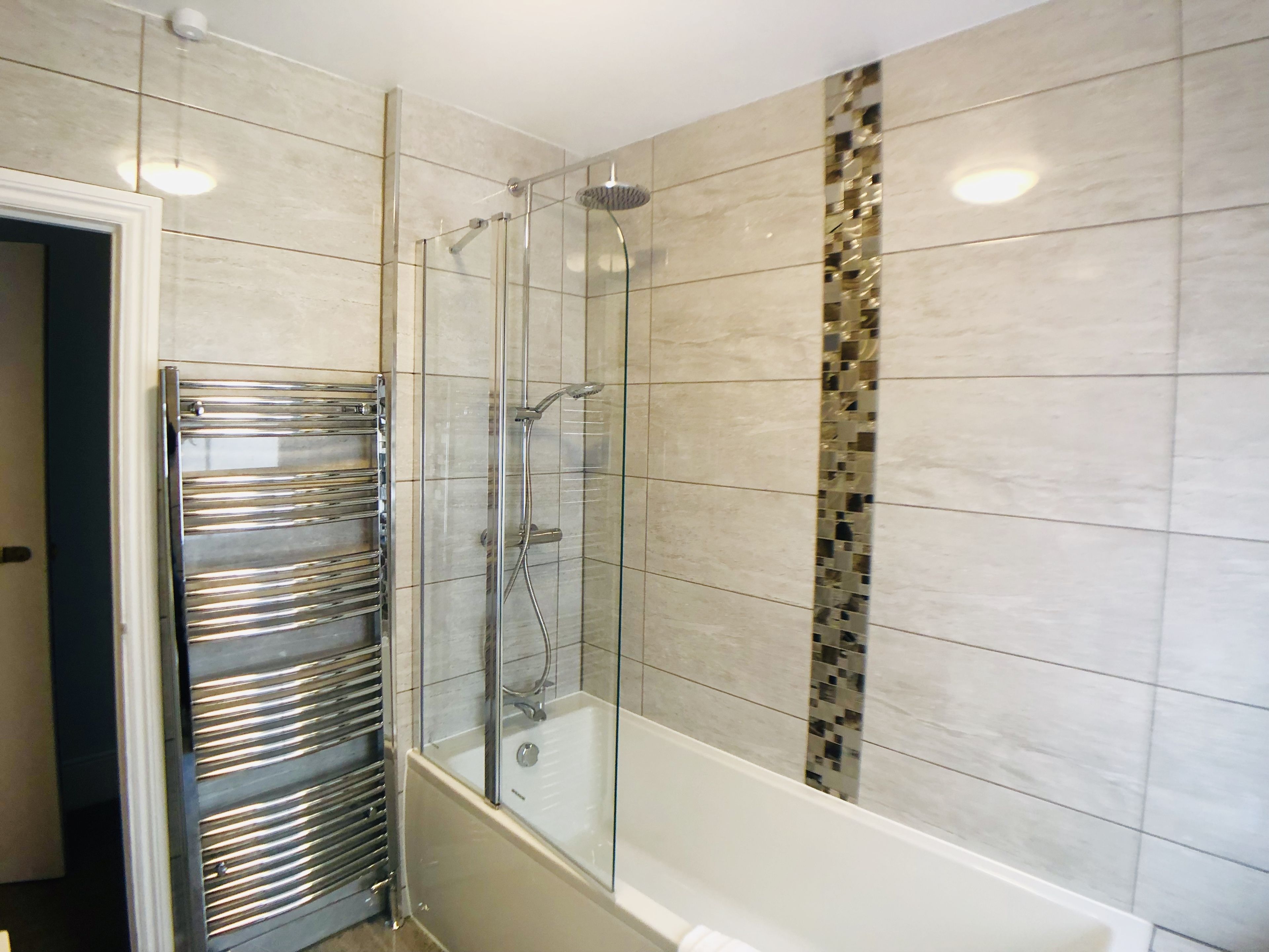 A modern bathroom with a glass-enclosed shower, a built-in glass bathtub, and a chrome towel rack.