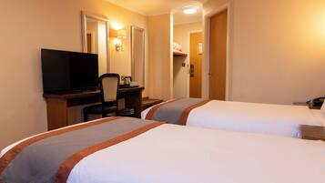A hotel room with two beds, a desk with a television, and a chair.