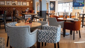 A modern restaurant with a bar area, patterned chairs, and a dartboard. - Weathervane Hotel by Greene King Inns (Stoke-on-Trent)