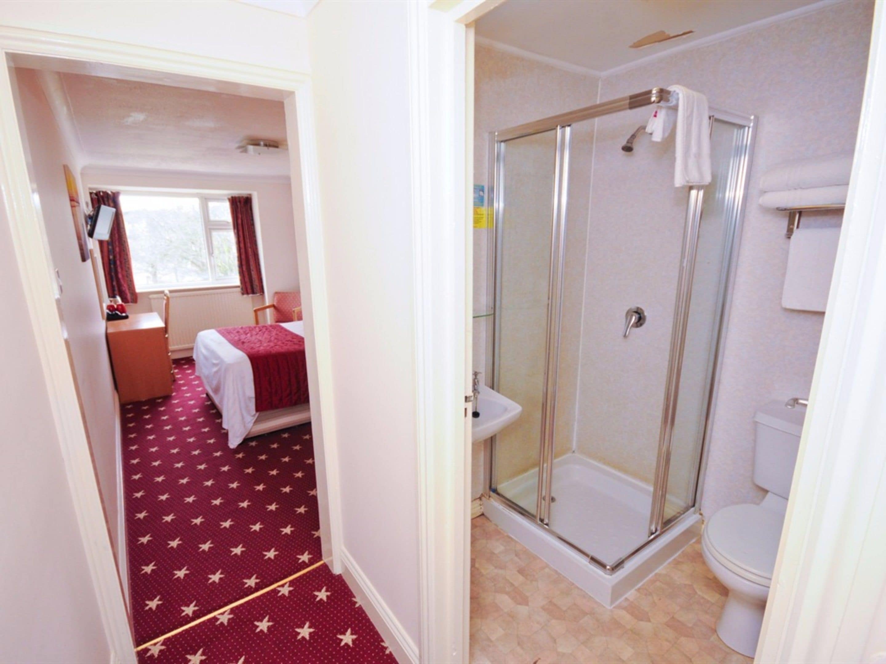 A hotel room with a bed, a shower, and a toilet.