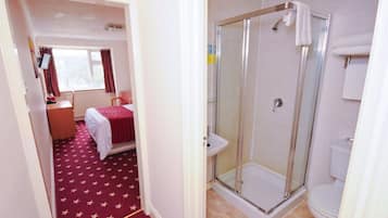 A hotel room with a bed, a shower, and a toilet.