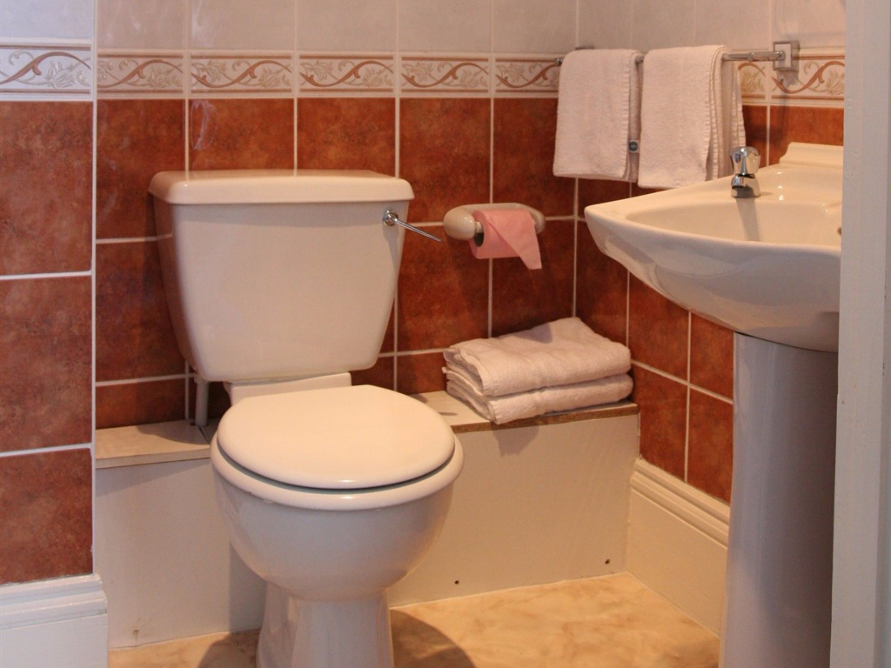 Un baño con inodoro, lavamanos y toallas apiladas.