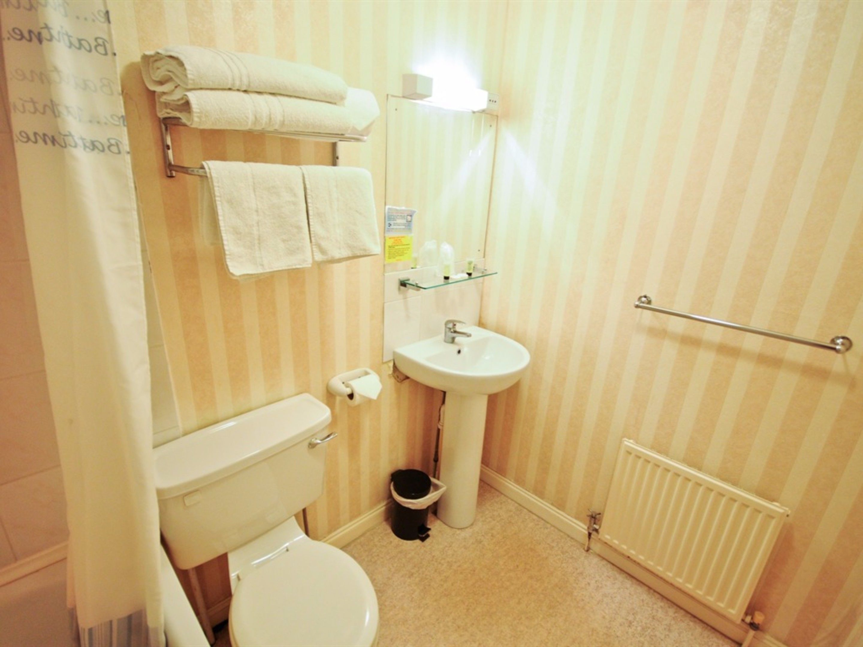 A bathroom with a toilet, sink, and towel rack.