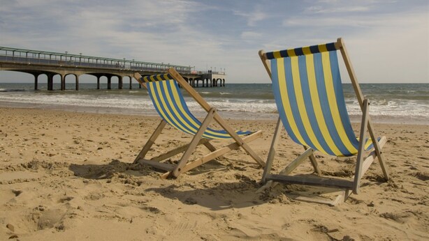 Two beach chairs on a sandy beach with a pier in the background. - Denewood Hotel - Guest Accomodation (Bournemouth)