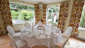 A dining area with a round table set for six, surrounded by white chairs. - The Mayfair Hotel (Bournemouth)