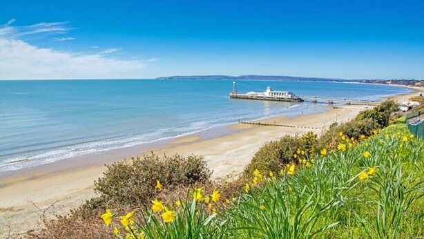 A coastal landscape with a beach, a pier, and a lighthouse. - The Mayfair Hotel (Bournemouth)