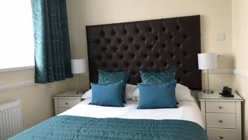 Quarto de hotel bem arrumado com uma cama grande, duas mesas de cabeceira e uma cabeceira.