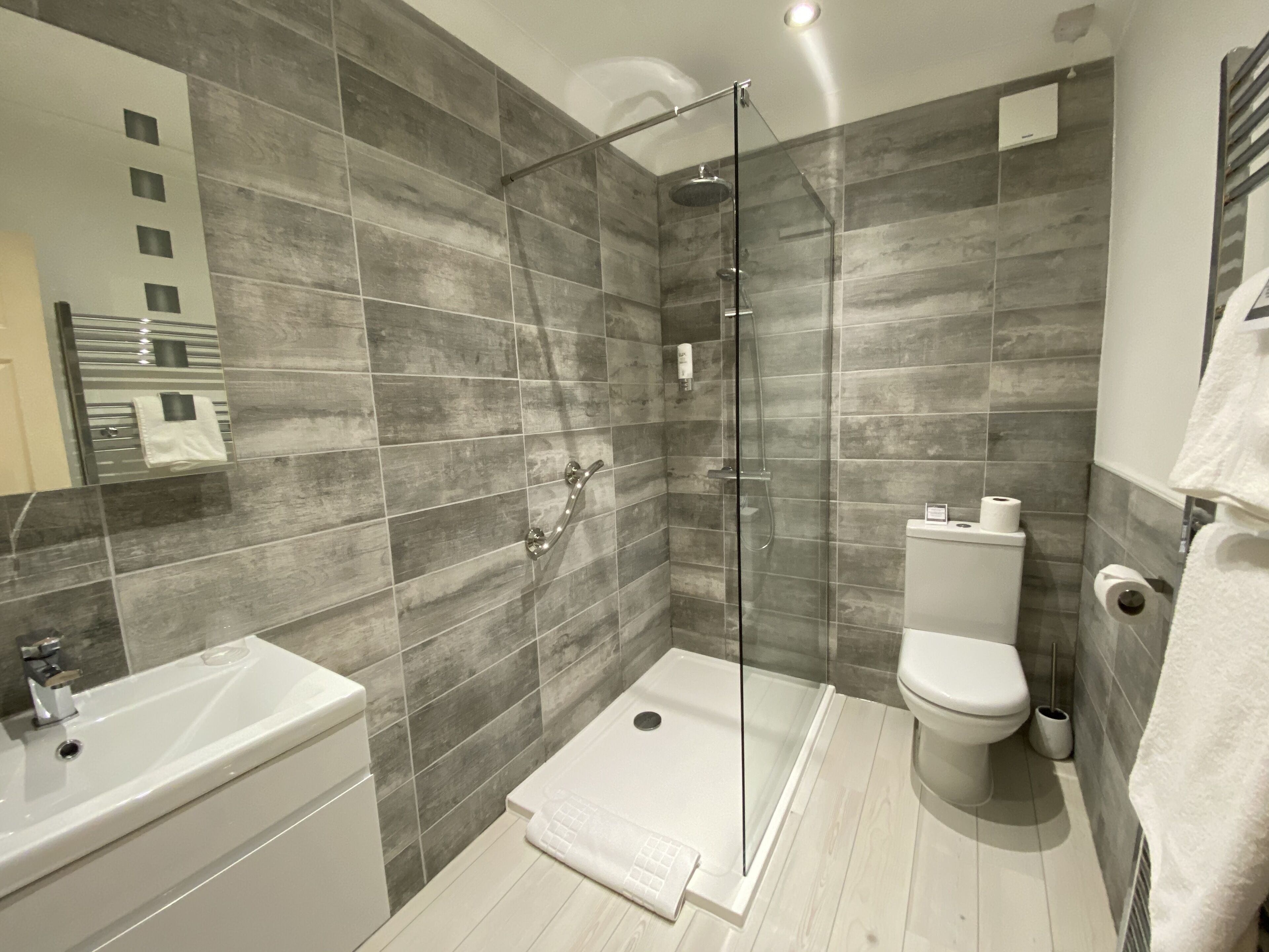Un baño moderno con ducha de vidrio, inodoro blanco y lavamanos.