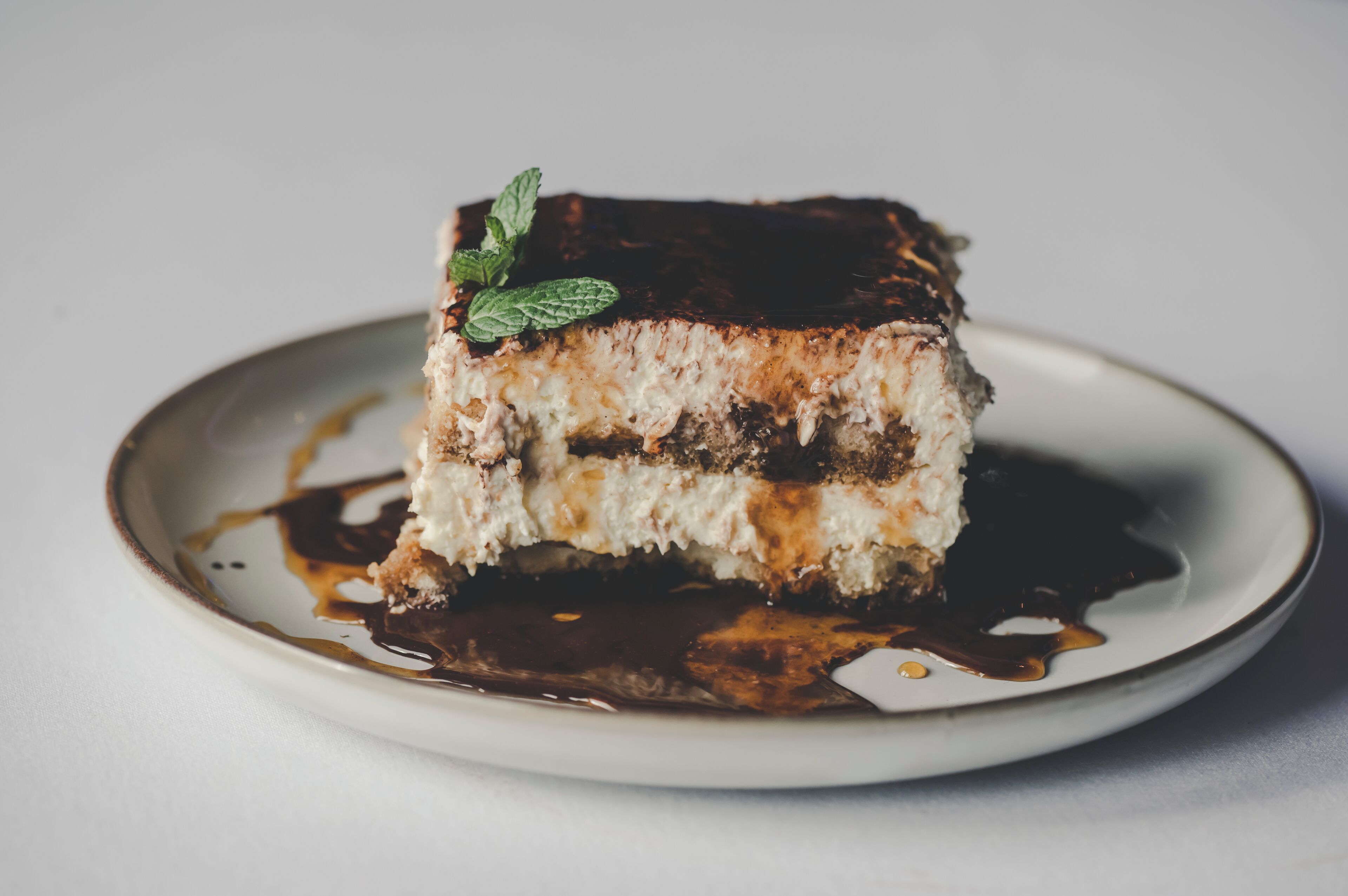 Una porción de pastel con capas y una decoración de menta en un plato.