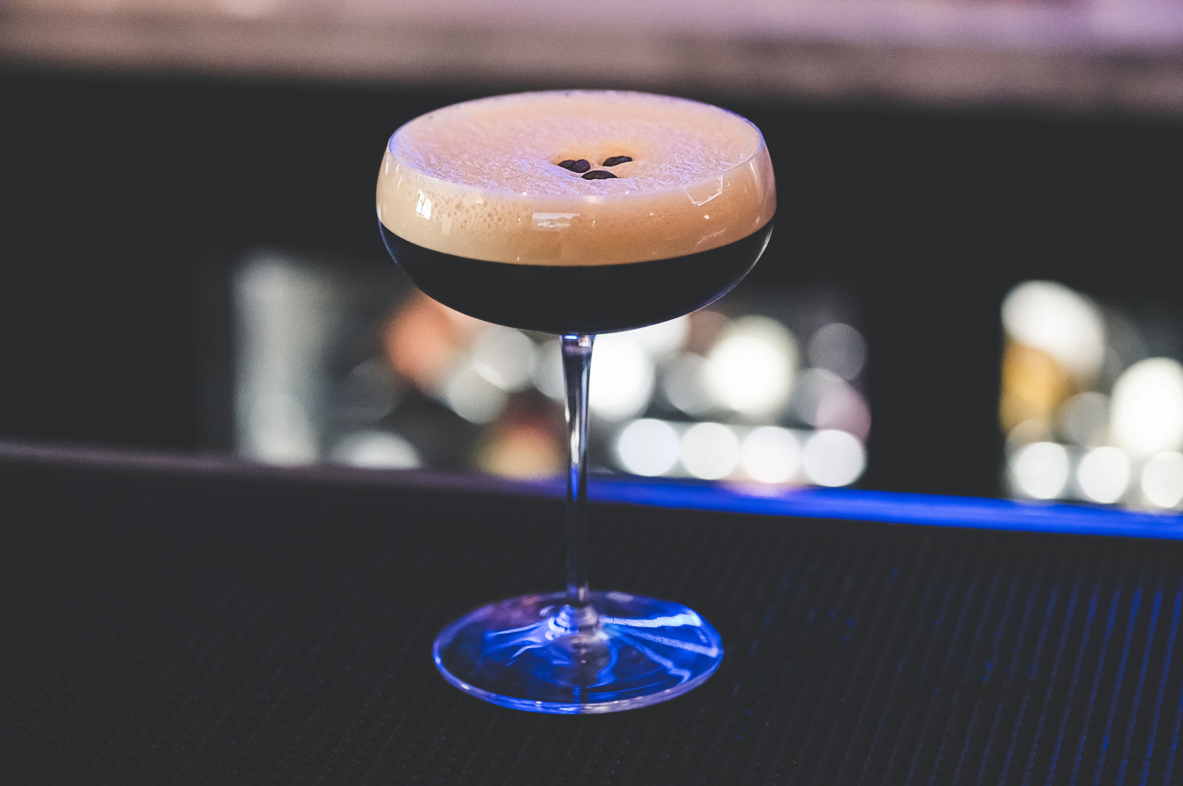 A cocktail in a coupe glass on a bar counter.