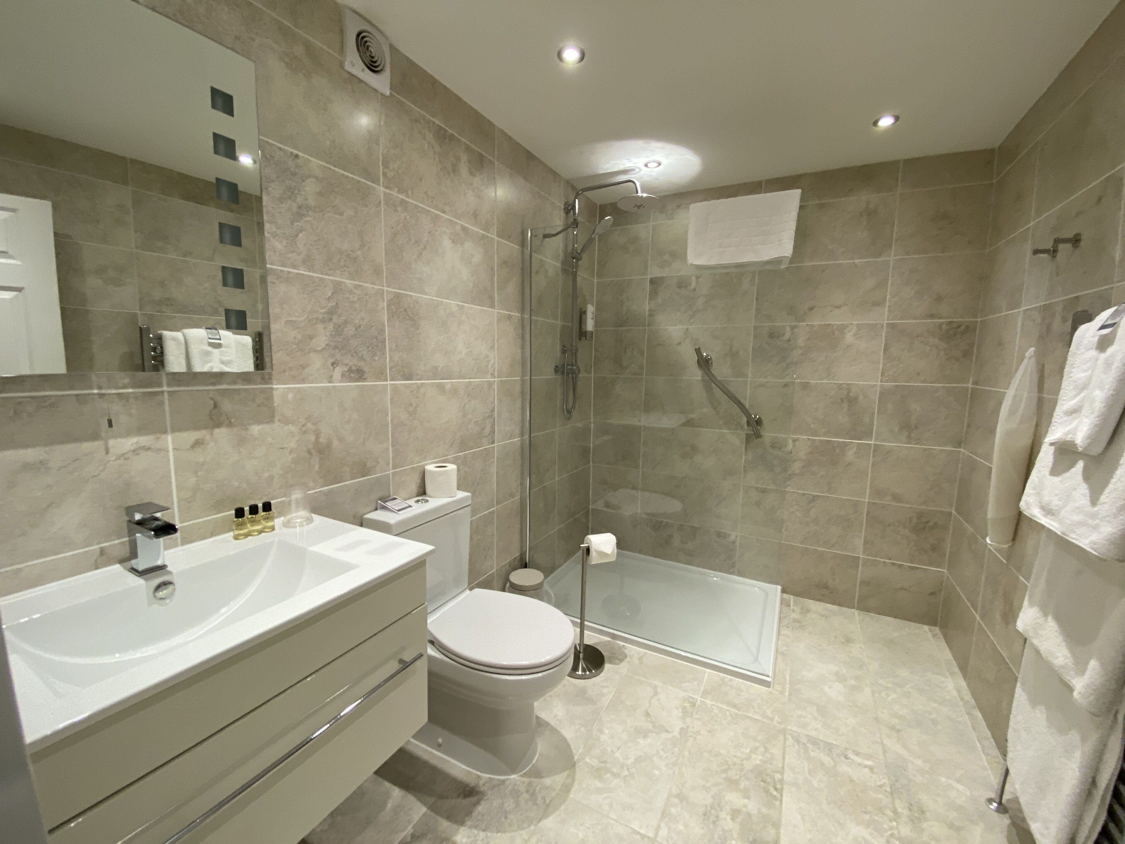 Un baño moderno con un lavamanos grande, inodoro y cabina de ducha de vidrio.