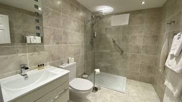 Un baño moderno con un lavamanos grande, inodoro y cabina de ducha de vidrio.